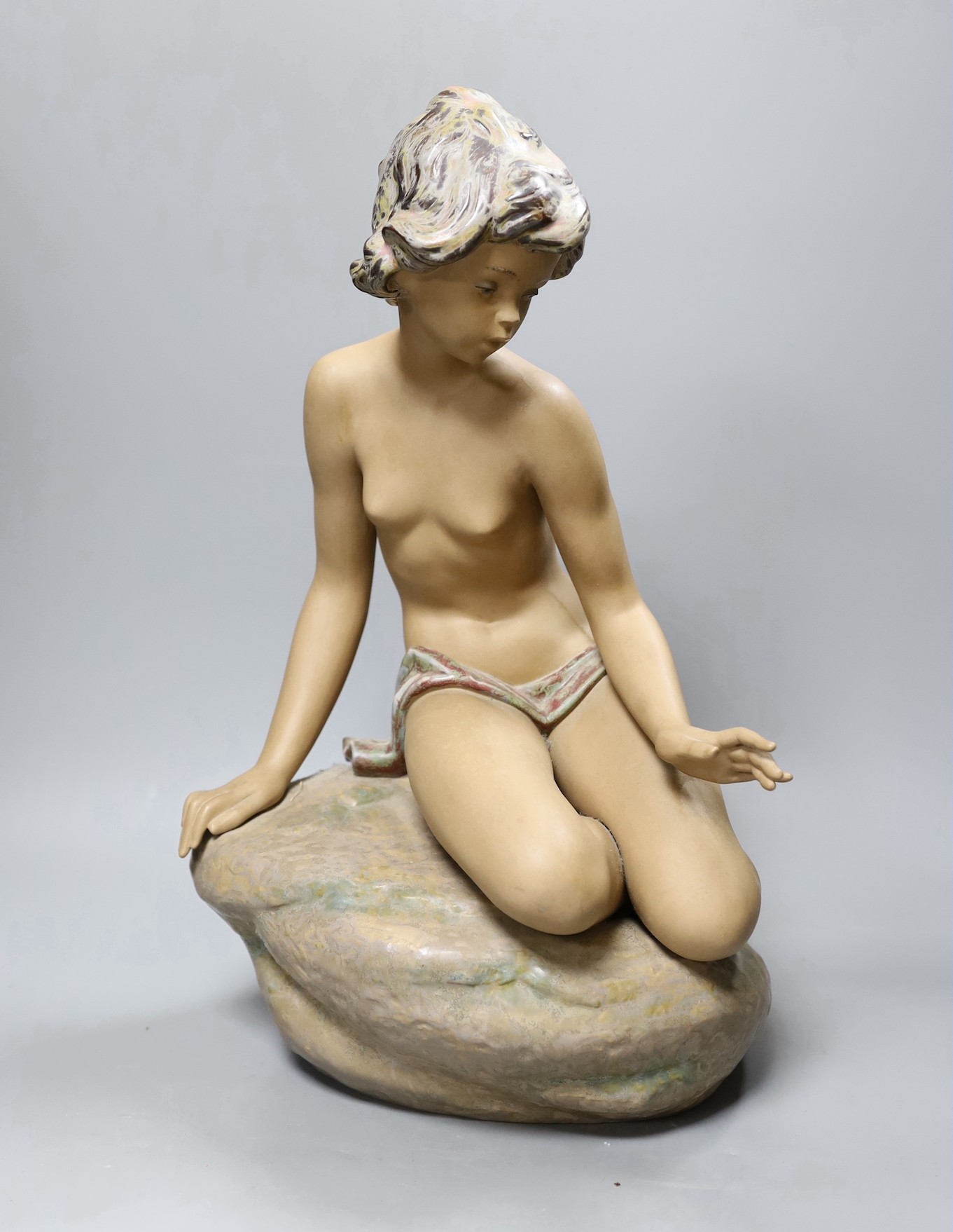 A large Lladro stoneware figure of a young girl seated on a rock, 42cm